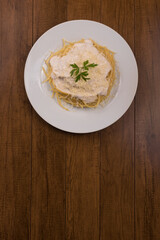 Pasta with bechamel sauce with grated cheese and parsley leaves. Vertical top photo with centered food with bottom space for text.