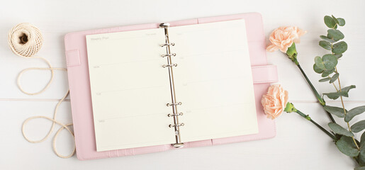 Open planner and flowers. Workspace with notebook. Freelance business, organization, wedding planning