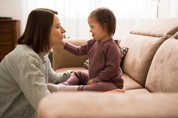 Girl with down syndrome touching face of her mother while sharing her love