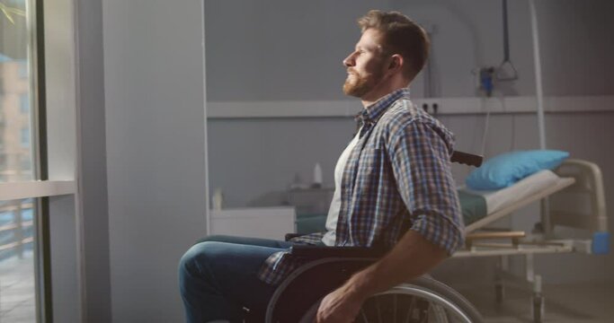 Man on wheelchair in clinic room looking through window and smiling