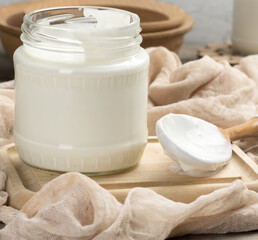 Obraz na płótnie Canvas homemade yogurt in a glass transparent jar on a wooden table