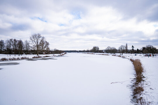 beautiful frozen river called werdersee completely covered in snow with snowy dike and cloudy sky in bremen in winter