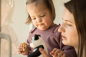 Girl with down syndrome holding cookie and looking at her panda toy