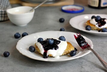 Whole grain pancakes with blueberries,yoghurt and jam on white plate