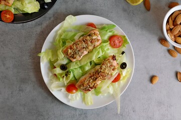 Fresh salad leaves with cherry tomato, olive with and roasted salmon with almont crust