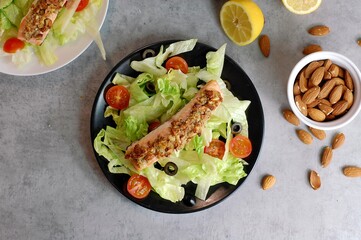 Fresh salad leaves with cherry tomato, olive with and roasted salmon with almont crust