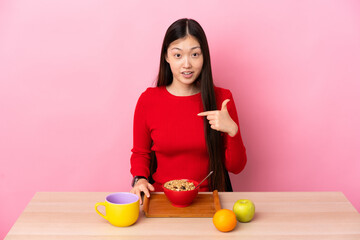 Young Chinese girl  having breakfast in a table with surprise facial expression