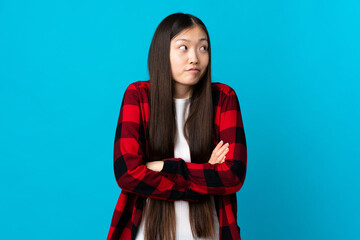 Young Chinese girl over isolated blue background making doubts gesture while lifting the shoulders