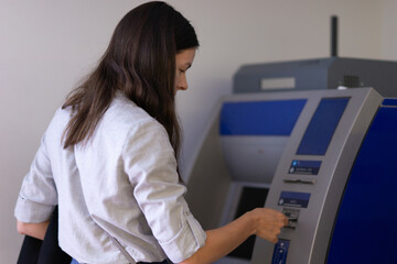 Young woman uses ATM to withdraw cash or pay for services,