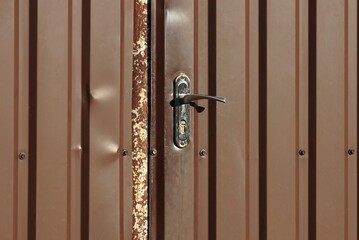 one old black metal doorknob on a brown closed iron door on the street