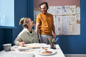 Man looking with tenderness at his girlfriend while she drawing