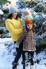 family portrait in the winter forest, mother and children posing near snowy fir trees, beautiful nature