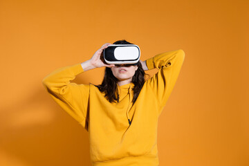 young woman with a virtual reality device on a yellow background.