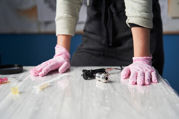 Tattoo artist wearing protective pink medical gloves standing at the table