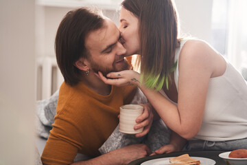 Woman sitting at the bed and kissing her husband at the chick