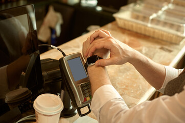 Man using smart watch to pay in restaurant. NFC contactless convenient payment service