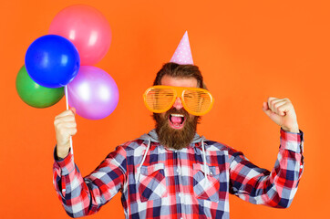 Party time. Joy, fun and happiness concept. Happy Man with balloons. Bearded man in party cap and big glasses.