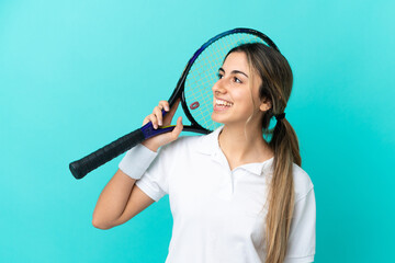 Young caucasian woman isolated on blue background playing tennis and looking up