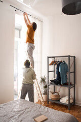 Woman holding ladder while her husband standing on it © Yakobchuk Olena