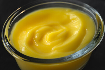 Lemon pudding in a glass bowl extremely close up on dark background