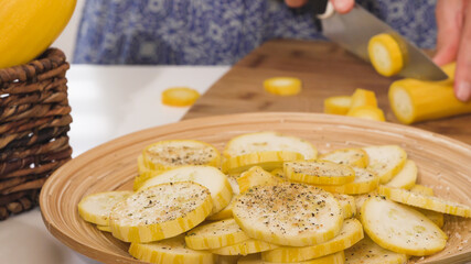 Zucchini slices on a plate, seasoning with garlic salt and fresh ground pepper. Baked zucchini with cheese and spices recipe