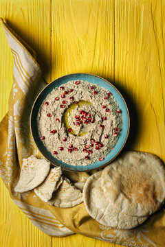 Baba ganoush or mutabal, Middle Eastern eggplant dip sauce garnished with pomegranate seeds with a rustic napkin and pita bread