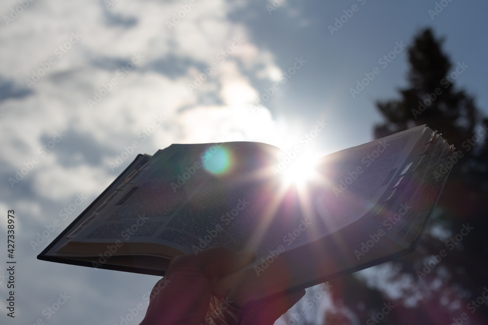 Wall mural open bible with sunlight and sky behind