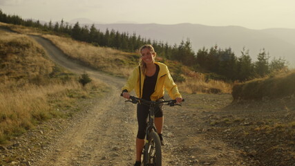 Fototapeta premium Woman on bicycle riding on path. Female bicyclist exercising in landscape
