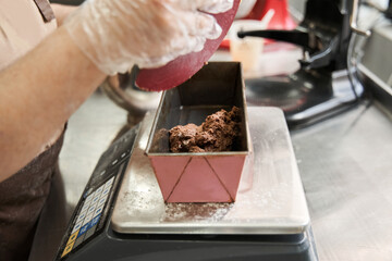 Woman baker putting fresh dough at the tank standing at the scales