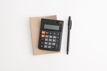 Calculator, notebook and pen on a white background
