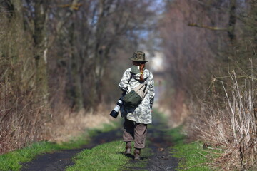 Professional wildlife photographer woman with camera on road to forest
