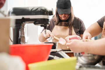 Female baker wearing apron standing at the kitchen and holding the scapula