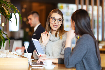 Two girls having a meeting at a modern cafe. Happy smiling expressions,