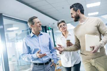 Concentrated young businessman in shirt standing with his colleagues at the hallway