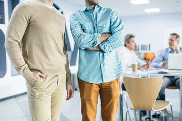 Fototapeta premium Cropped view of the positive male colleagues are standing at the corridor