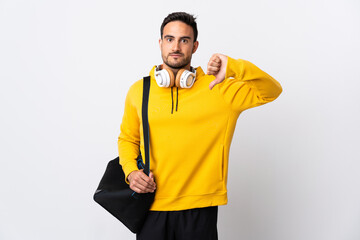 Young sport man with sport bag isolated on white background showing thumb down with negative expression