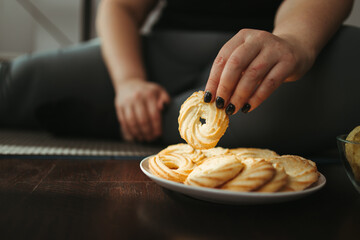 Overweight woman sitting on mat and eating cookies