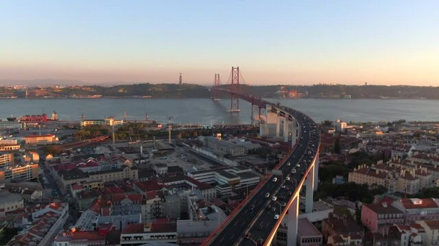 Aerial tilt up shot showing traffic on 25 of April bridge (Portuguese: Ponte 25 de Abril) over the Tagus River at sunset in Lisbon, Portugal.