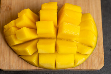 ripe mango cut into cubes on a dark gray background