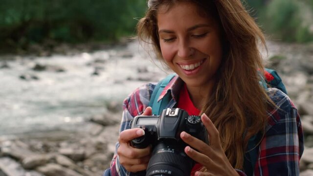 Hiker using photo camera. Smiling woman taking photos of mountain landscape 