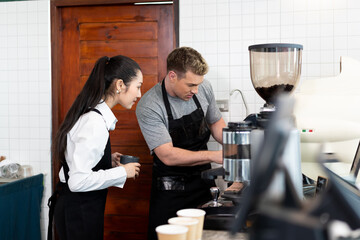 Barista cafe wearing apron and prepare coffee grinder pour at coffee shop with happy and smiling. Worker making coffee on steam espresso coffee machine