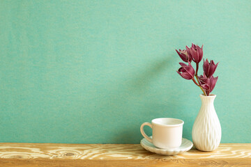 Coffee cup with flower on wooden table. green background