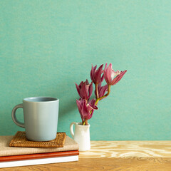 Notebook, mug cup, flower on wooden desk. green background. Work and study place