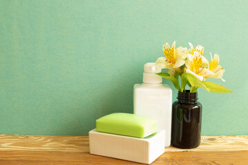 White bottle and soap with flowers on wooden shelf. Bathroom skin care and spa concept