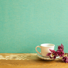 Coffee cup with flower on wooden table. green background