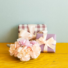 Gift boxes with carnation flowers on wooden table. blue background