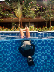 A pregnant woman in upside down position in swimming pool at a resort.