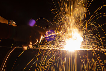 Iron welding close-up, sparks do not wear gloves. Welding sparks and fumes It can be dangerous to...