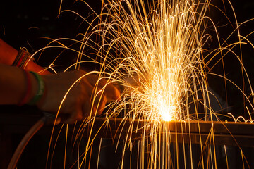 Iron welding close-up, sparks do not wear gloves. Welding sparks and fumes It can be dangerous to health.