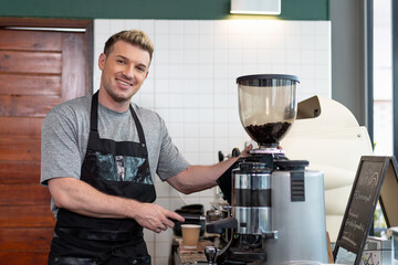 Barista cafe  wearing apron and prepare coffee grinder pour at coffee shop with happy and smiling. Worker making coffee on steam espresso coffee machine